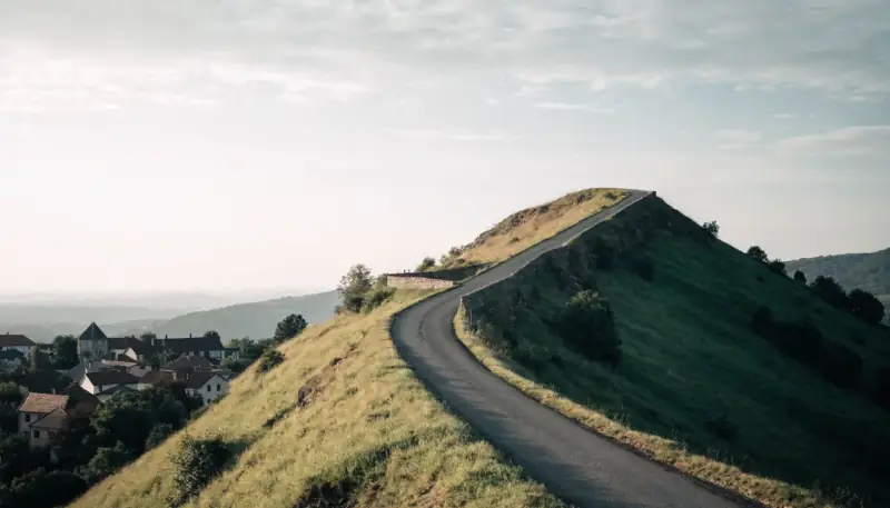 Bir kasabanın üstünde yeşil yamaca tırmanan yol
